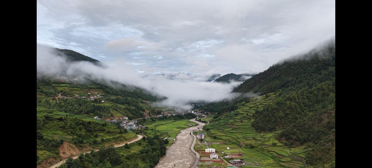 Terraced fields and a river running through the mist-covered Dirang valley